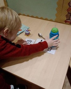 Young boy sitting at a table playing with Makaton Symbol cards