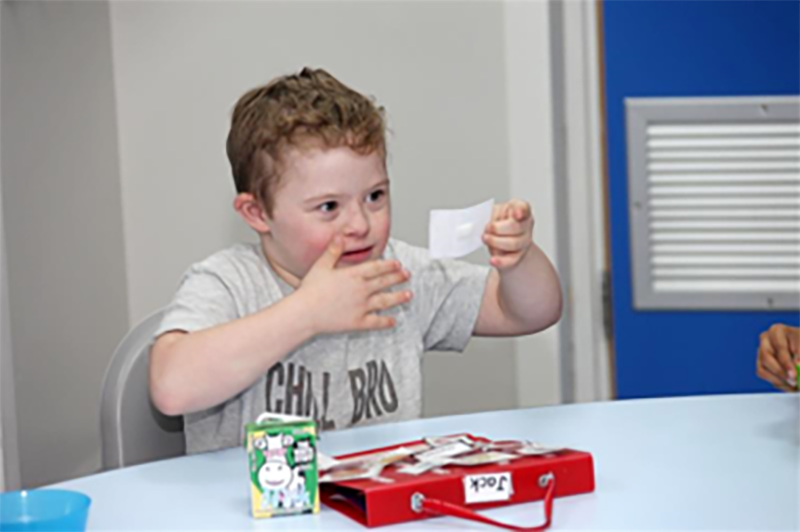 Young boy sitting at a table playing with symbol cards